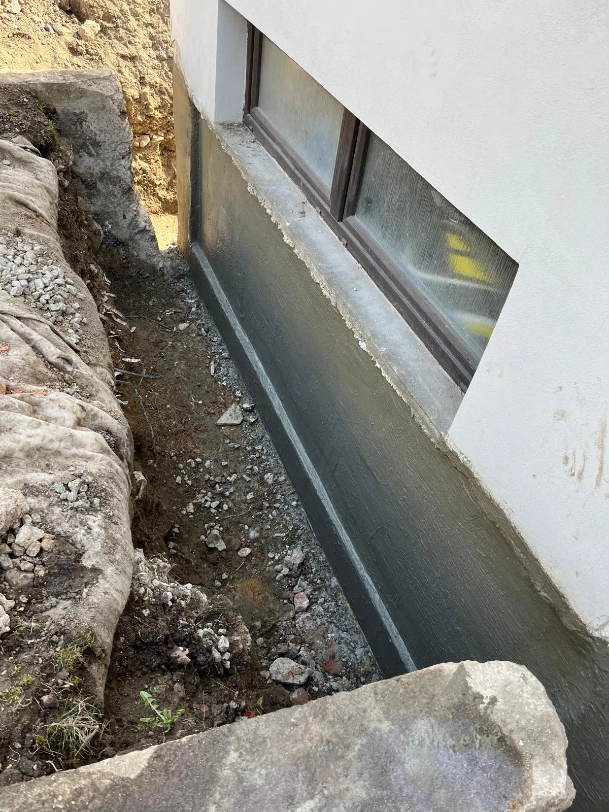 Nová hydroizolace na patě základové zdi v odkopané rýze