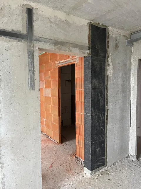 Železobetonový sloup ovinutý uhlíkovou tkaninou vedle zděné příčky